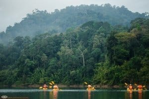 Guests kayak over Cheow Larn Lake at Rainforest Camp, floating bungalow accommodation in Khao Sok